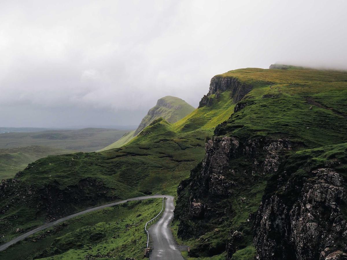 A road winding through green highlands toward cliffs